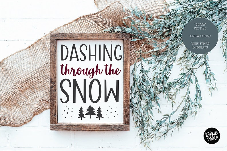Pu&ograve; includere: Un cartello di legno bianco con il testo "Dashing through the snow" in lettere nere. Il cartello &egrave; decorato con piccoli fiocchi di neve neri e tre alberi di pino neri in silhouette. Il cartello &egrave; incorniciato in legno marrone.