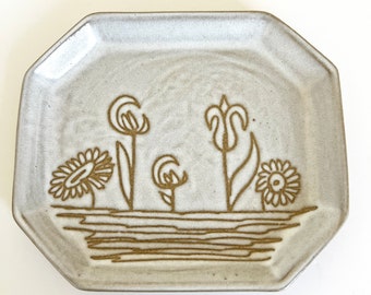 May include: A white ceramic octagonal plate with a brown floral design. The plate features stylized flowers and leaves.