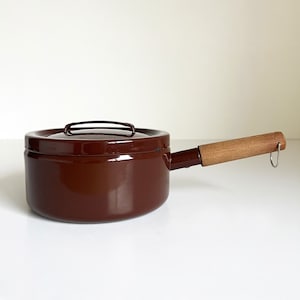 May include: A brown enamel saucepan with a wooden handle and a lid. The saucepan has a metal loop on the handle.