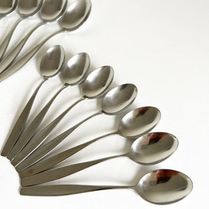 May include: A set of 10 silver spoons arranged in a fan shape on a white background.