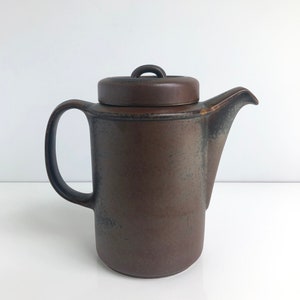 Puede incluir: Una cafetera de cerámica marrón con tapa y asa negra. La cafetera tiene un esmalte moteado.