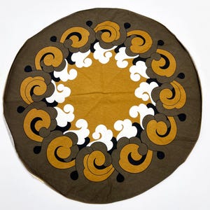 May include: A round brown tablecloth with a white and gold swirl pattern.