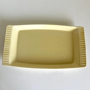 May include: A pale yellow rectangular serving tray with a decorative pattern around the edge.