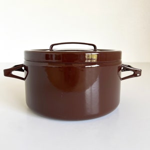 May include: A brown enamel pot with two handles and a lid. The pot is made of metal and has a glossy finish.