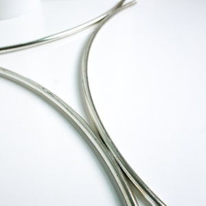 May include: Two silver metal hoops, curved and joined at the top, forming a decorative stand.