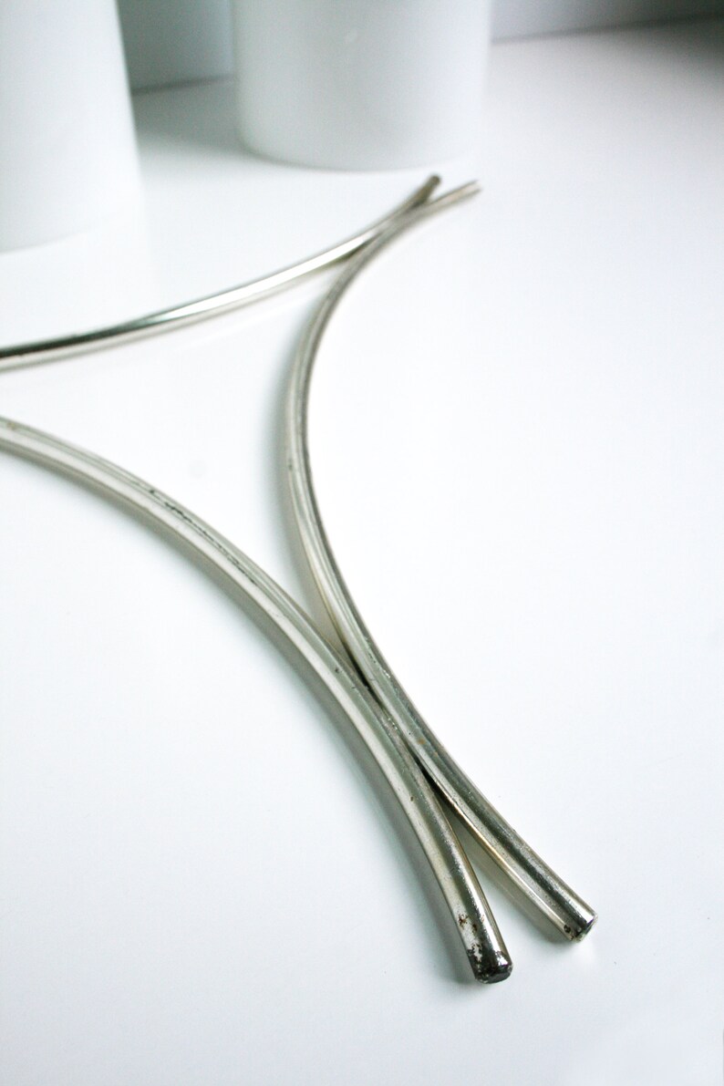 May include: Two silver metal hoops, curved and joined at the top, forming a decorative stand.