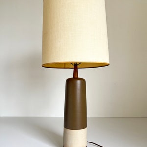 May include: A mid-century modern table lamp with a brown and white ceramic base and a white linen shade.