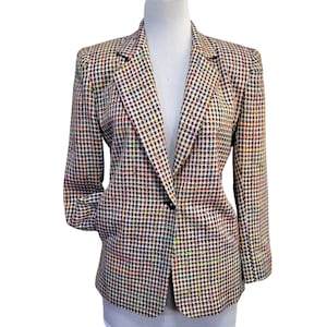 May include: A long-sleeve blazer featuring a multi-colored checkered pattern with black, white, and vibrant flecks of red, blue, yellow, and green. The garment has a notched lapel, structured shoulders, and a single-button closure at the center front.