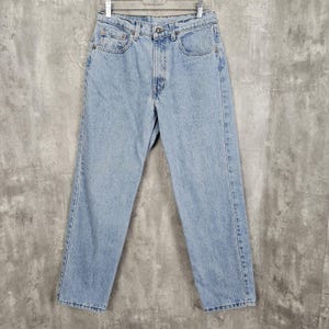 May include: Light blue denim jeans with a straight leg fit. The jeans have a classic five-pocket style and a button fly.