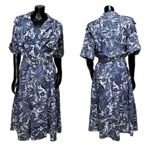 Könnte beinhalten: Ein blaues und weißes Blumenkleid mit Kragen, kurzen Ärmeln und einem Gürtel in der Taille. Das Kleid hat einen weiten Rock und eine lockere Passform.