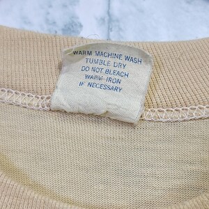 May include: A white care tag with blue text that reads "Warm Machine Wash, Tumble Dry, Do Not Bleach, Warm Iron If Necessary."