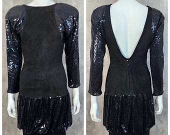 May include: A black dress with a sequined bodice and sleeves. The dress has a scoop neckline and a fitted silhouette. The skirt is made of a soft, flowing fabric.
