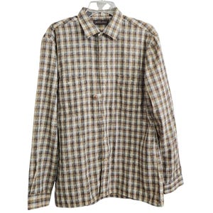 May include: A long-sleeve button-down shirt featuring a plaid pattern in shades of brown, tan, and white. The shirt includes a standard collar, a front button placket, and two chest pockets with button closures. The label reads Jondy Place.