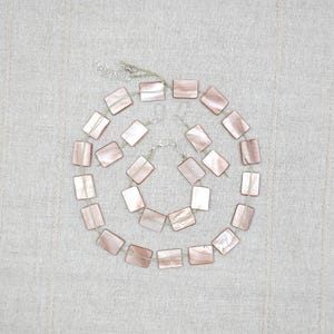 Set di gioielli in lino e madreperla beige, composto da collana, bracciale e orecchini pendenti rettangolari a forma di conchiglia, stile boho-chic minimalista e naturale, ideale come regalo estivo. Codice articolo: 7142.