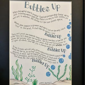 May include: A framed print with a blue and green illustration of bubbles and seaweed. The print features the lyrics to the song "Bubbles Up" by Jimmy Buffett. The lyrics are written in a whimsical, handwritten style.