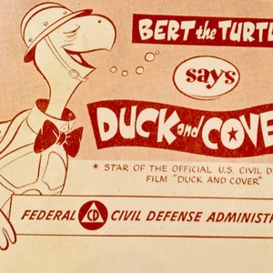 May include: A vintage poster with a cartoon turtle named Bert, wearing a helmet and bow tie. The poster promotes the U.S. Civil Defense film "Duck and Cover", with the words "Duck and Cover" prominently displayed.