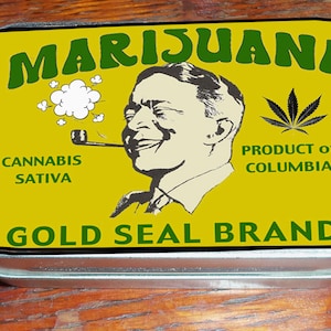 Puede incluir: Una lata de metal amarilla con una ilustración verde y blanca de un hombre fumando una pipa. El texto en la lata dice "Marijuana, Cannabis Sativa, Producto de Colombia, Marca Gold Seal".