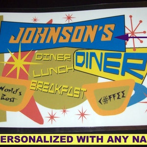 Puede incluir: Un letrero de estilo retro para un restaurante con el texto "Johnson's Diner" en amarillo y azul. El letrero también incluye las palabras "Diner", "Lunch", "Breakfast" y "World's Best" en una fuente estilizada. El letrero está personalizado con el texto "Your Name Here" en un cuadro morado.