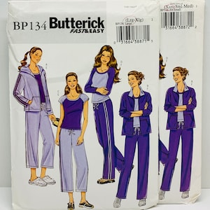 May include: A sewing pattern for women's clothing, featuring four different outfits. The pattern is called "Butterick Fast & Easy" and has the number BP134. The outfits include a purple and white tracksuit, a purple and white top with matching pants, a purple top with light blue pants, and a purple jacket with matching pants.