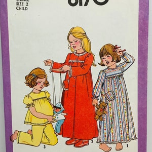 May include: Simplicity sewing pattern number 8170 for a child's nightgown. The pattern includes three different styles: a red nightgown with a white collar and cuffs, a blue and white striped nightgown with a white collar and cuffs, and a yellow nightgown with a white collar and cuffs. The pattern is for sizes small, 2, and child.
