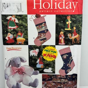 Può includere: Una collezione di modelli Simplicity Holiday con ornamenti in feltro, una calza e un agnello. Il modello include istruzioni per realizzare una calza di Natale, una scena della natività, un agnello e altri ornamenti. Il modello è etichettato "Plus Easy Felt Fun Ornaments Kids can make!"