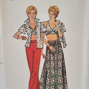 Może przedstawiać: Wzorzec szycia vintage do dwuczęściowego stroju. Wzorzec jest dla rozmiarów 13 i 14. Strój zawiera bluzkę z krótkim rękawem i dekoltem w kształcie owijania oraz długą spódnicę z geometrycznym nadrukiem. Wzorzec pochodzi od Butterick i ma numer 3701.