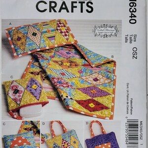 May include: A sewing pattern for a quilt and four bags. The quilt is made of colorful fabric with a diamond pattern. The bags are made of the same fabric and have different shapes and sizes. The pattern is called "Artful Offerings" by designer Karina Hirtle.