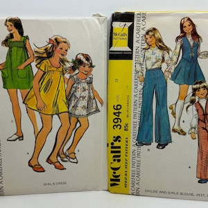 Puede incluir: Dos patrones de costura vintage de McCall's. El patrón de la izquierda es para un vestido de niña y está numerado 3601. El patrón de la derecha es para una blusa, chaleco, falda y pantalones para niños y niñas y está numerado 3946. Ambos patrones están etiquetados como "Carefree Pattern" y tienen un precio de 85 céntimos.