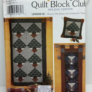 May include: Simplicity Quilt Block Club Holiday Edition Lesson #6 pattern featuring a quilt block design with a Christmas tree motif. The pattern includes instructions for making a cushion, a wall hanging, and a table runner.