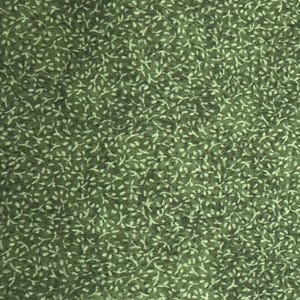 Puede incluir: Primer plano de una tela verde con un patrón repetido de pequeñas formas blancas en forma de hojas. Las hojas están dispersas por la superficie, creando una apariencia texturizada. La tela tiene un aspecto ligeramente descolorido.