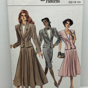 Op de afbeelding: Vogue Patterns naaipatroon nummer 9977 voor maten 12-14-16. Het patroon toont drie vrouwen die verschillende variaties van een rok- en jaspak dragen. De eerste vrouw draagt een bruine rok en jas, de tweede vrouw draagt een grijze rok en jas, en de derde vrouw draagt een roze rok en jas.