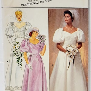 May include: A vintage sewing pattern for a wedding dress. The pattern is for size 12 and features two different styles of dresses. One dress is white with a lace bodice and puff sleeves. The other dress is a light pink color with a sweetheart neckline and puff sleeves. The pattern is from Butterick and is number 4766.
