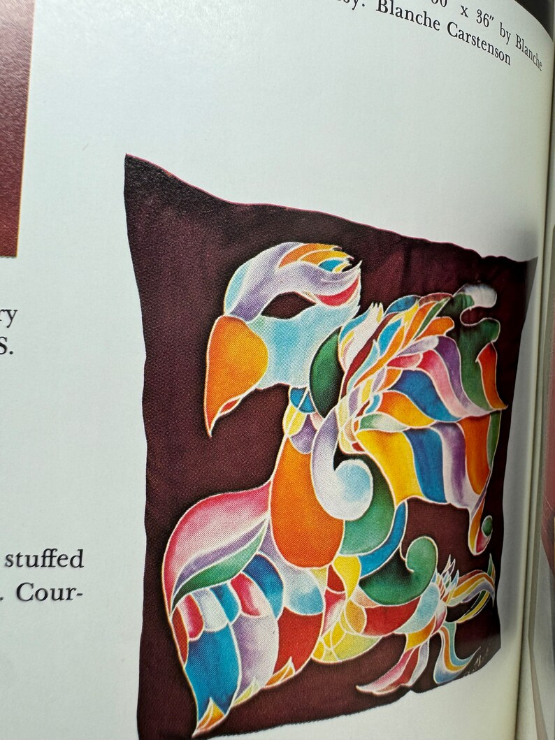 May include: A colorful, abstract design of a bird with a long tail, painted on a dark brown fabric pillow. The pillow is approximately 36 inches by 36 inches.