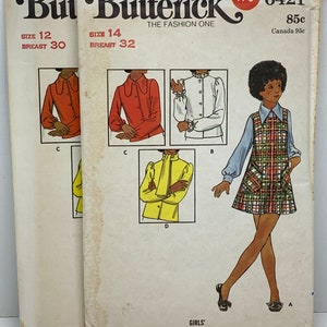 May include: A vintage sewing pattern for a girl's dress and blouse. The pattern is from Butterick and is number 6421. The pattern includes sizes 7-14. The dress is plaid and the blouse is yellow with a ruffled collar.