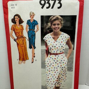 May include: Simplicity pattern 9373, size 12 Miss, featuring illustrations of three different dresses. The cover is red with the Simplicity logo and the price. The dresses include a wrap dress, a button-down dress, and a dress with a colorful print.