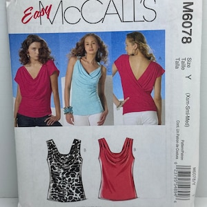 May include: Sewing pattern for a women's top with a cowl neck. The pattern includes four different styles of tops, including a sleeveless top with a leopard print, a red top, a blue top, and a pink top. The pattern is for stretch knits only.