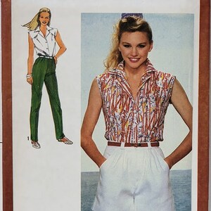 Puede incluir: Patrón de costura Simplicity número 9552 para una blusa sin mangas y pantalones cortos. El patrón es para la talla 14 miss. La modelo lleva una blusa blanca con un diseño estampado rojo y blanco y pantalones cortos blancos. El patrón está sobre un fondo marrón.