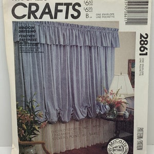 May include: A sewing pattern for window dressing, featuring a blue and white patterned fabric with a ruffled edge. The pattern is called "Window Dressing" and includes instructions for making valances and shades. The pattern is from McCall's Crafts and is number 2861.