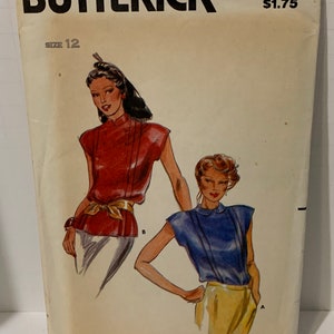 Puede incluir: Un patrón de costura vintage de Butterick, número 6921, para una blusa sin mangas. El patrón es para la talla 12 y cuesta $ 1,75. El patrón muestra dos modelos usando la blusa en diferentes colores, uno en rojo y otro en azul.