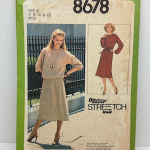 May include: Simplicity sewing pattern number 8678 for a knit dress. The pattern is for sizes 8, 10, and 12. The pattern includes two different dress styles, one with a long sleeve and one with a short sleeve. The pattern is for stretch knit fabric.