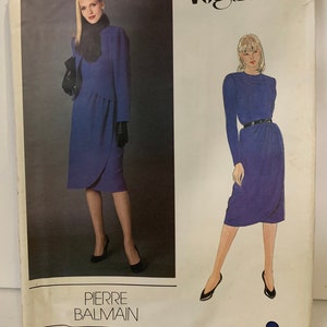 Pode incluir: Um padrão de costura vintage Vogue para um vestido de Pierre Balmain. O padrão é para um vestido azul com saia de envelope e mangas compridas. O número do padrão é 2577.