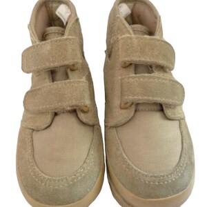 May include: A pair of beige suede and canvas high-top sneakers with velcro closures.
