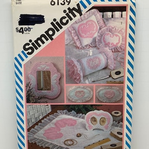 May include: Simplicity sewing pattern number 6139 for a set of home decor items. The pattern includes instructions for making a pillow, a bolster pillow, a picture frame, a vanity tray, and a small picture frame. The pattern is for one size and costs $4.00.