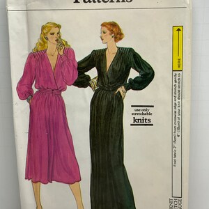 Pode incluir: Padrão de costura Vogue Patterns com duas mulheres em vestidos longos. O número do padrão é 7450, tamanho 14. A capa inclui o texto "use apenas malhas elásticas" e um medidor de elasticidade de malha.
