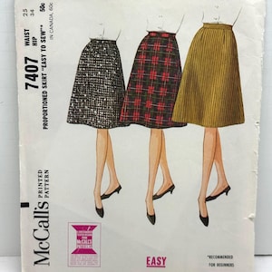 May include: Vintage McCall's sewing pattern 7407 for a proportioned skirt. The pattern features illustrations of three skirt designs: a black and white patterned skirt, a red and black plaid skirt, and a gold striped skirt. The pattern is labeled "Easy to Sew."