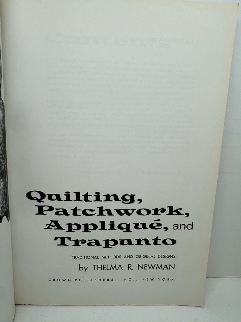 May include: Book cover with the title "Quilting, Patchwork, Appliqu&eacute;, and Trapunto" in black text. The subtitle is "Traditional Methods and Original Designs" in smaller black text. The author is "by Thelma R. Newman" and the publisher is "Crown Publishers, Inc., New York".
