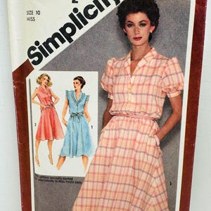Op de afbeelding: Een Simplicity naaipatroon envelop 9867 voor een jurk in maat 10 miss. De hoes toont een foto van een persoon in een roze en geel geruite jurk met korte pofmouwen en illustraties van twee andere jurkvarianten in roze en blauw.