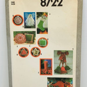 Può includere: Modello di cucito Simplicity numero 8722 per decorazioni natalizie. Il modello include istruzioni per realizzare una varietà di ornamenti, tra cui una calza, una gonna per l'albero, un portacandele e un appendiporta. Il modello è stampato su uno sfondo bianco con accenti rossi e verdi.