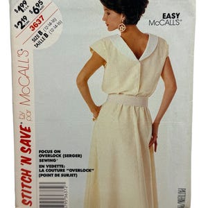 Pode incluir: Um padrão de costura McCall's vintage com uma mulher num vestido creme com riscas verticais. O vestido tem uma gola branca e botões na frente. O padrão inclui o texto "STITCH 'N SAVE" e "EASY McCall's".