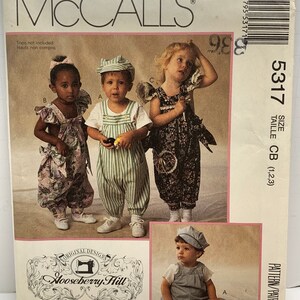 May include: A sewing pattern for children's overalls. The pattern is from McCall's and is for sizes CB (1, 2, 3). The pattern includes three different styles of overalls, all with a striped pattern. The pattern is called "Hooseberry Hill Original Designs".